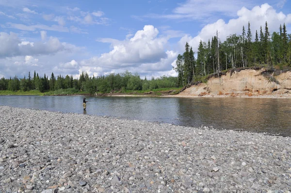 Kiezelstrand ten noorden van de rivier en de visser. — Stockfoto