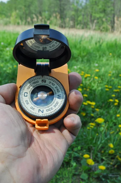 Compass in hand, against the background of blooming meadows. — Stock Photo, Image