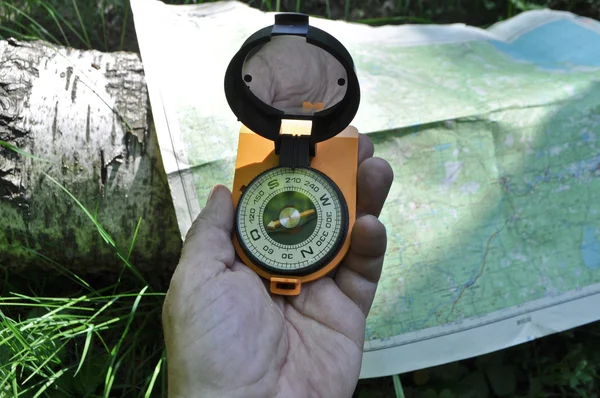 Kompass in der Hand, vor dem Hintergrund der Karte. — Stockfoto