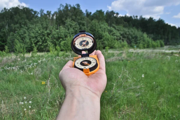 Kompas w ręku, na tle lasu. — Zdjęcie stockowe