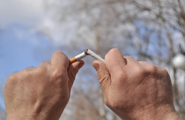 Un cigarrillo roto en su mano. — Foto de Stock