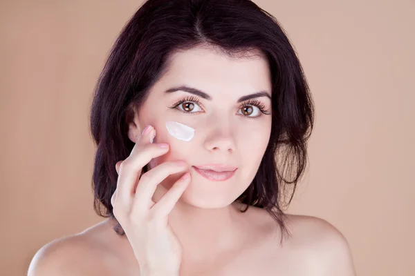 Menina bonita colocar o creme na pele — Fotografia de Stock