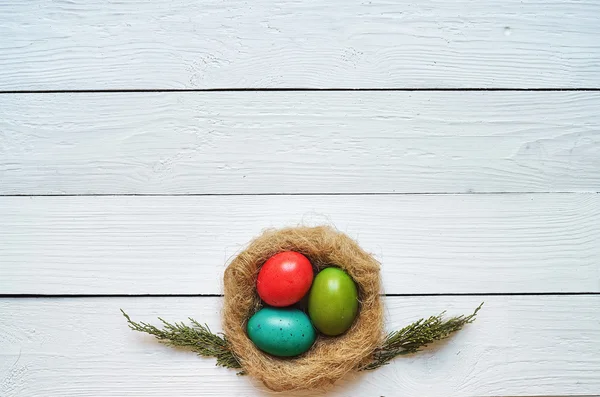 Nest colored eggs wreath on white wooden planks background. Easter greeting postccard template. Space for copy, text, lettering. — ストック写真