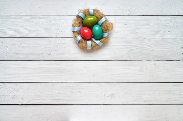 Nest bunte Eier Kranz auf weißen Holzplanken Hintergrund. Ostergruß Postkartenschablone. Raum für Kopie, Text, Schrift. — Stockfoto