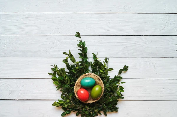 Nest bunte Eier Kranz auf weißen Holzplanken Hintergrund. Ostergruß Postkartenschablone. Raum für Kopie, Text, Schrift. — Stockfoto