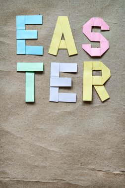 Easter colored paper origami folded lettering on craft eco background. Postcard template. Space for text, copy.