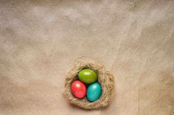 Ninho com ovos coloridos sobre fundo de papel eco artesanal. Modelo de cartão postal de Páscoa. Espaço para texto, cópia, letras . — Fotografia de Stock