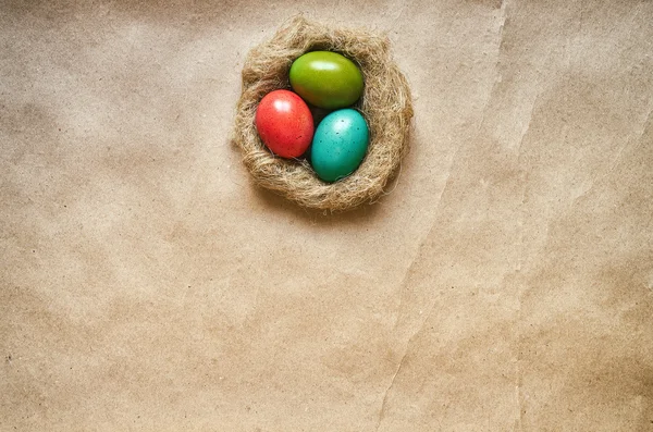 Nest with colored eggs on eco craft paper background. Easter postcard template. Space for text, copy, lettering. — ストック写真