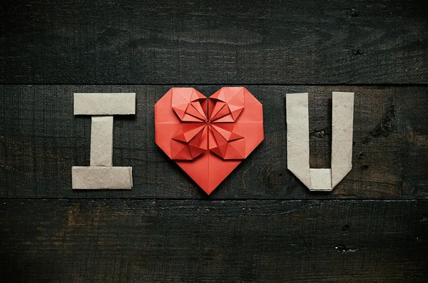 Origami I LOVE U letters on dark brown aged wood background. Red paper heart. Valentines day horizontal postcard.
