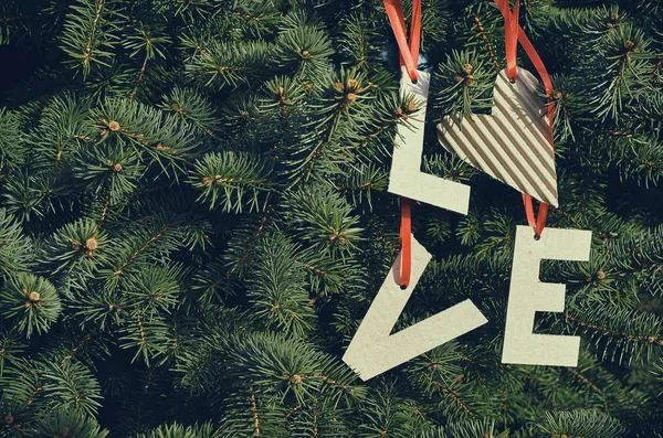 Lettere d'amore di cartone appese a strisce rosse su rami di pino verde. Modello di cartolina natalizia. Spazio per testo, copia, lettering . — Foto Stock