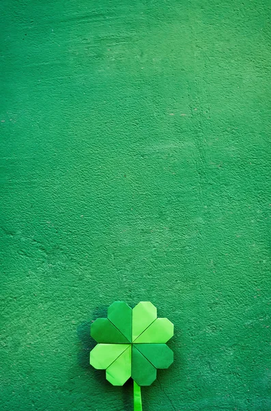 Hand holding paper origami green shamrock on wall background. Space for copy, lettering, text. St. Patrick's day postcard tempalte. — ストック写真