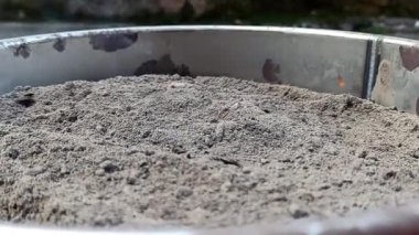Bir kabın içindeki topaklardan çıkan küllerin görüntüsü, kazandan çıkarılmış.