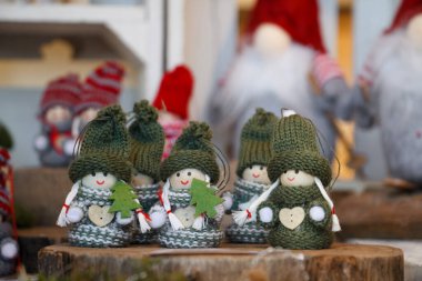 Şirin el yapımı, yeşil şapkalı Noel heykelcikleri, keçeli ağaçlar, ahşap tezgahlarda sergilenen kış detayları. Tatil tasarımları, zanaat temaları, mevsimlik promosyonlar için mükemmel sıcak bir festival sahnesi..