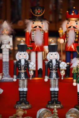 Geleneksel ahşap fındıkkıran heykelcikleri süslü üniformalı askerlerin yer aldığı kırmızı bir arka planda sergileniyor. Bayram pazarları ve mevsimlik tasarımlar için klasik Noel dekoru.