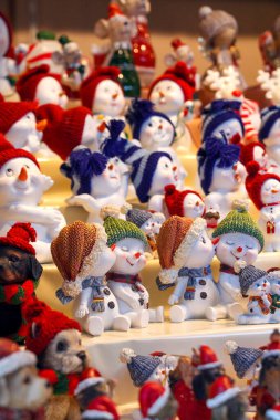 Renkli örgü şapkalı sevimli kardan adam heykelcikleri Noel alışverişi gösterisinde, eğlenceli kış dekoru ve tatil hediyesi fikri.