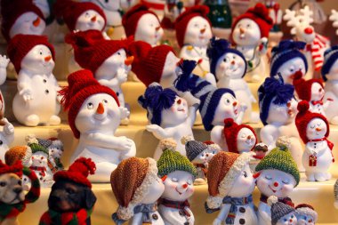 Renkli örgü şapkalı sevimli kardan adam heykelcikleri Noel alışverişi gösterisinde, eğlenceli kış dekoru ve tatil hediyesi fikri.