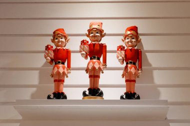 Noel 'de beyaz bir rafta hediye kutuları taşıyan üç cüce heykeli. Sıcak ışık, mevsimlik neşe, kış kutlaması ve geleneksel Noel dekoru içeren tatil dekorasyonu konsepti.