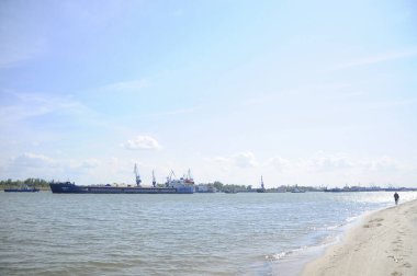 Don Nehri 'nin kumlu kıyısında bir adam yürüyor. Bir gemi bu kıyıda ilerliyor.