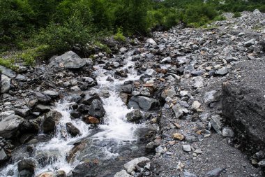 Midagrabindon şelaleleri vadide. Yazın Kuzey Kafkasya 'da dağlar. Bulutlarda dağın tepeleri.