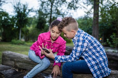 Akıllı telefondan komik bir şey izlerken gülen ve eğlenen iki küçük arkadaş.