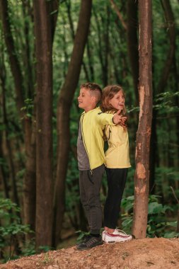 Güzel doğanın tadını çıkarıyorum. Kollarını kaldırmış küçük bir çocuk ve kız yeşil ormanda temiz havanın tadını çıkarıyorlar. Seçici odak