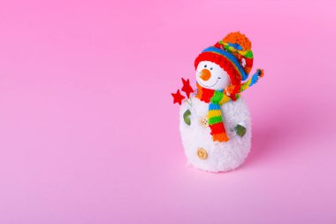 Açık pembe arka planda bir kardan adam. Kopyalama alanı olan minimum kış tatili konsepti.