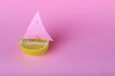 Taze meyve limonlu yatla güzel bir dekorasyon fikri, pembe arka planda yelkenli. - Yakın çekim. Ön manzara. Boşluğu, canlı yiyecekleri, özgürlüğü ve macera konseptini kopyala