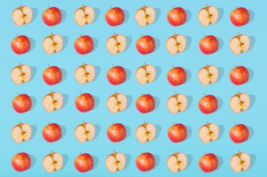 Mavi pastel arka planda taze elma ve elma parçalarının olağanüstü deseni var. Minimalist izometrik gıda konsepti. Düz yatıyordu