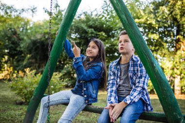 Küçük çocuk parkta güzel bir kızla sohbet ediyor ve eğleniyor. Güzel doğada iyi vakit geçiriyor. Seçici odak.