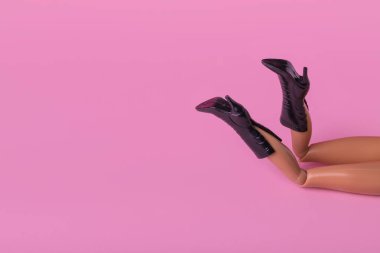 Çizmeli bebek bacaklı, yüksek topuklu, pastel pembe arka planda yaratıcı kompozisyon. Kopya alanı ile en düşük moda ve güzellik kavramı.