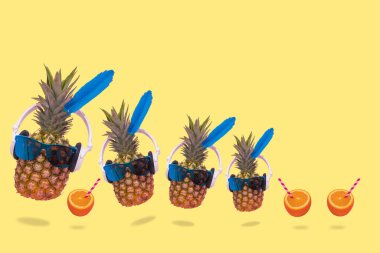 Neşeli ve neşeli ananasları olan, güneş gözlüğü takan, kulaklık takan ve taze portakal suyu kullanan yaratıcı bir yaz fikri. En az eğlence, parti, moda, moda ve yaz içeceği sahnesi. Kopyalama alanı için boş alan.