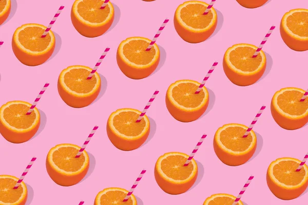Fruit pattern of fresh orange half with straws on bright pink background. Minimal Pop art design, creative summer concept. Copy space