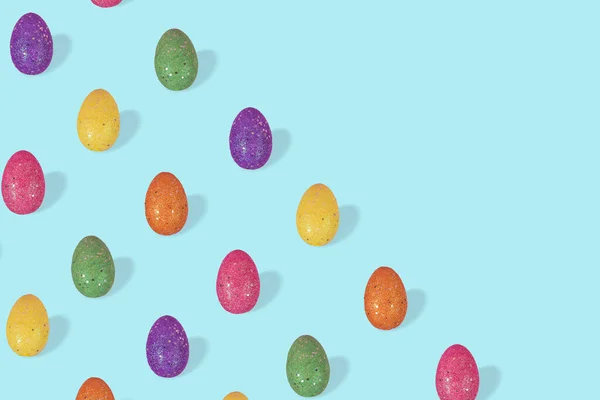 Creative Easter pattern made of colorful eggs arranged on pasel blue background. Minimal easter concept. Trendy Easter card with free space for text.