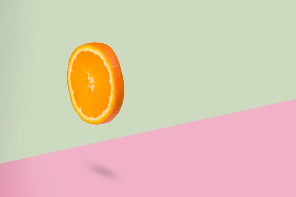 在浅绿色和粉色的背景上 用新鲜的橙子做一个最小的创意 采购产品维生素 健康的饮食 化妆品和美的概念 一片橙子漂浮在空中 有飞果的创意概念 — 图库照片