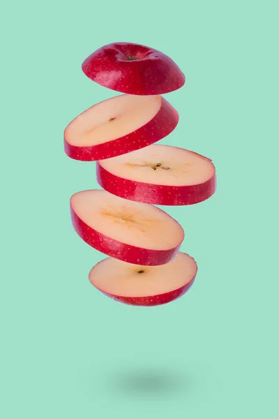 緑の背景に熟したリンゴを浮遊させます ビタミン 健康的な食事の概念 最小限の果物のアイデア スライスしたリンゴが空中に浮かんでいます 空飛ぶ果物と創造的なコンセプト — ストック写真