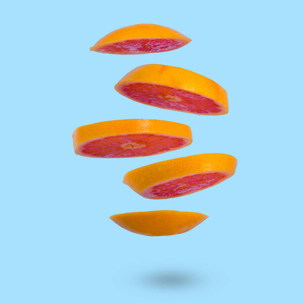 Floating levitating ripe grapefruit on a light blue background. Vitamins, healthy diet concept. Minimal fruit idea. Sliced grapefruit floating in the air. Creative concept with flying fruits.