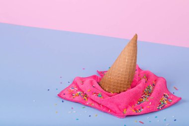 Dondurma külahından ve pastel mavisi ve pembeye dökülen bezden oluşan yaratıcı minimal bir fikir. Minimalist yaz konsepti: Yemek ve temizlik. Boşluğu kopyala