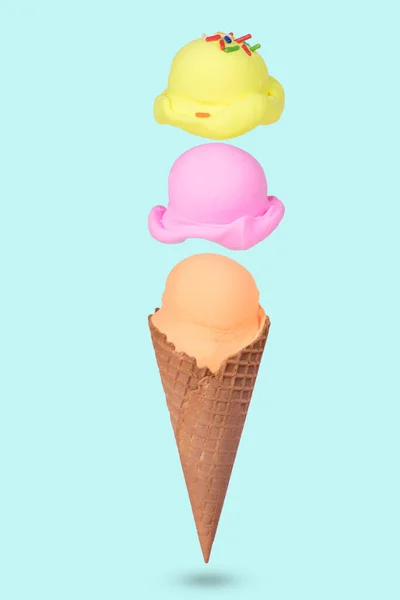パステルブルーの背景にカラフルなアイスクリームのスクープが浮かぶアイスクリームコーンで作られた創造的なアイデア ミニマルな夏のコンセプト — ストック写真