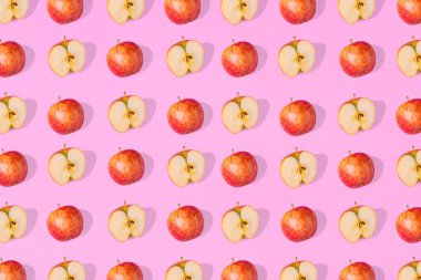 Pembe arka planda taze elma ve elma parçaları. Minimalist sağlıklı gıda konsepti. Düz yatıyordu