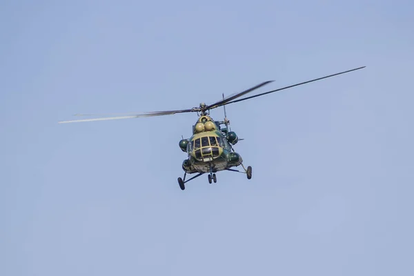 A military helicopter painted in camouflage color is flying high in the sky. Close up.