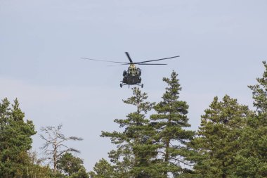 Kamuflaj rengine boyanmış askeri bir helikopter gökyüzünde yükseklerde uçuyor. Kapat..