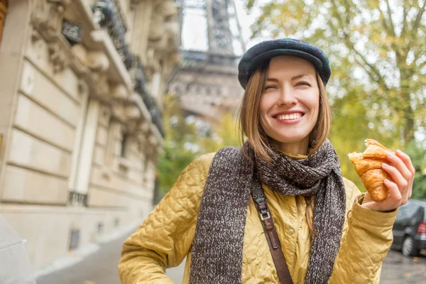 通りでクロワッサンを食べる美しい女性が背景にエッフェル塔と良い暖かい天気を楽しんで — ストック写真