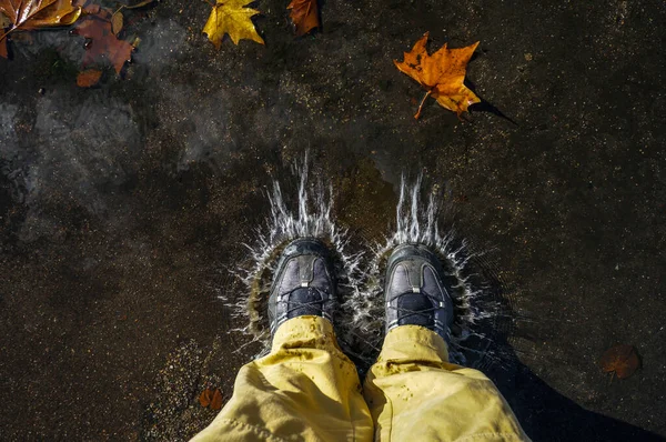 Man walking down the street during rain, walking in puddles