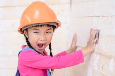 Marangoz çocuk ahşap duvarda zımpara işi yapıyor.