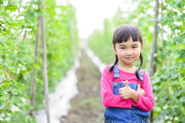 Çocuk bahçıvan çiftlikte baş parmağını gösterdi.