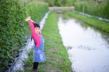 Çocuk bahçıvan hasat öncesi ürünü kontrol ediyor.