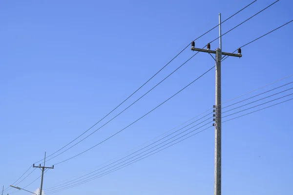 蓝天背景的高压电线杆 图库照片