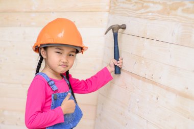 Küçük marangoz kız tahta duvarda çekiç gibi çalışıyor.