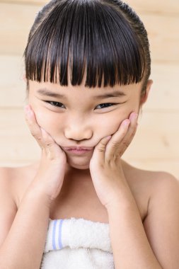 Küçük kız banyo yapar ve ahşap duvarda poz verir.