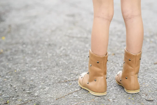 Çizmeli çocuk asfalt yolda bekliyor.